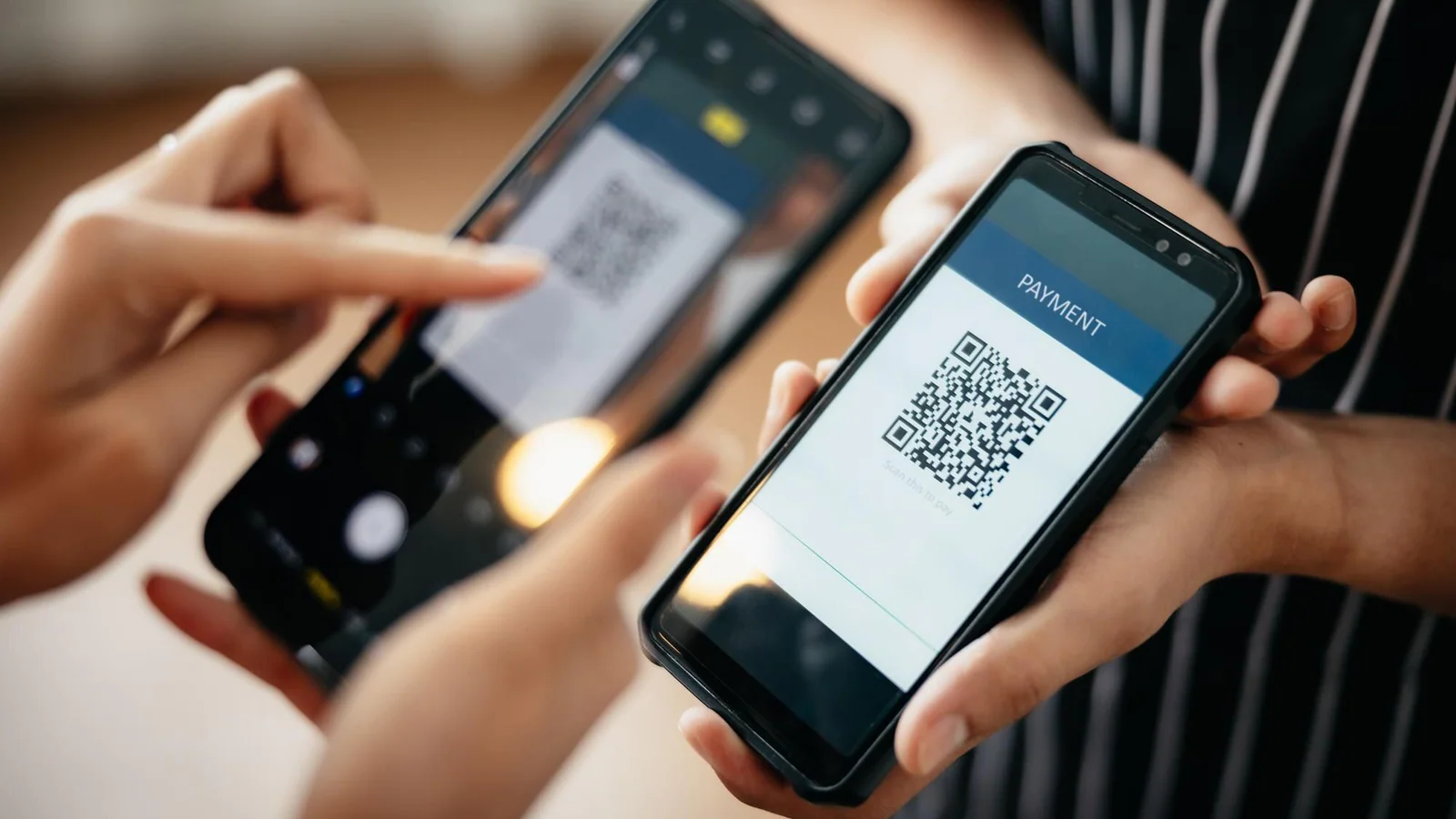 Hand håller smartphone och skannar QR-kod som illustration av realtidsbetalningar och UPI