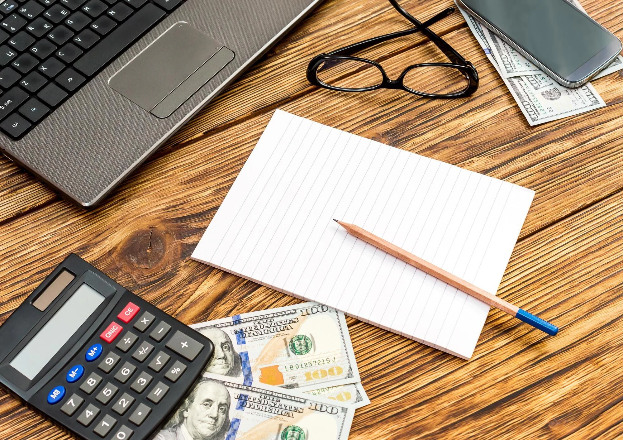 Laptop, miniräknare och pengar på en arbetsplats som illustrerar olika former av företagsfinansiering