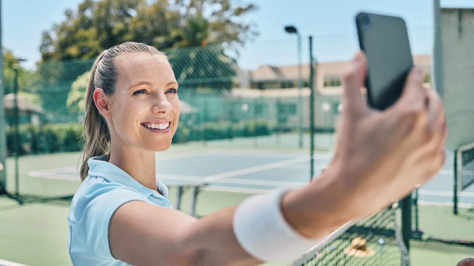 Illustrationsbild av tennisspelare som tar selfie med mobil vid tennisbana