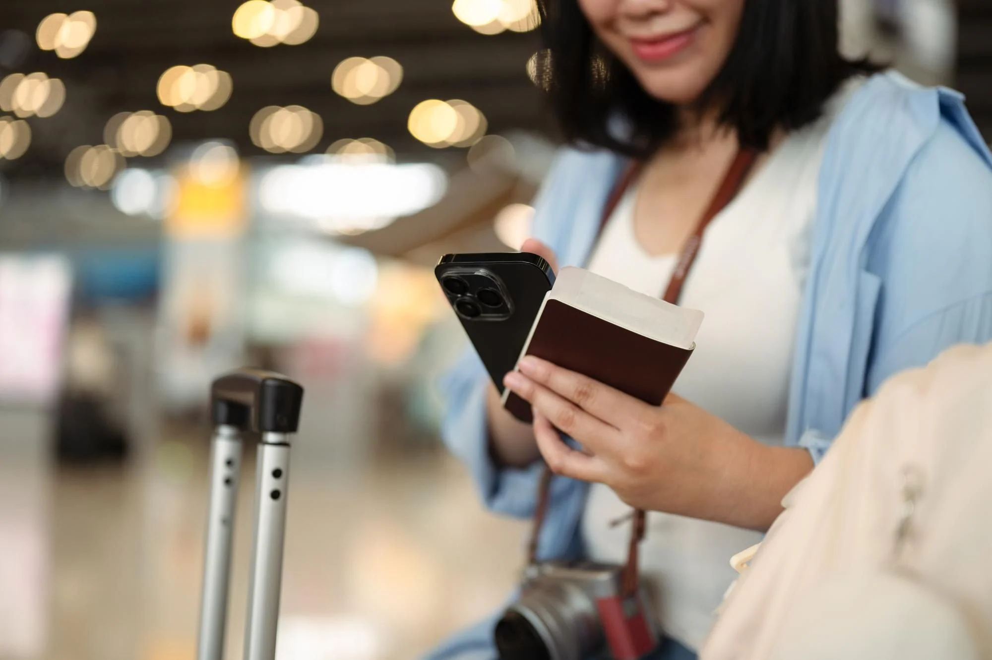 Resenär med pass och mobiltelefon jämför och hanterar flygbokning på flygplats