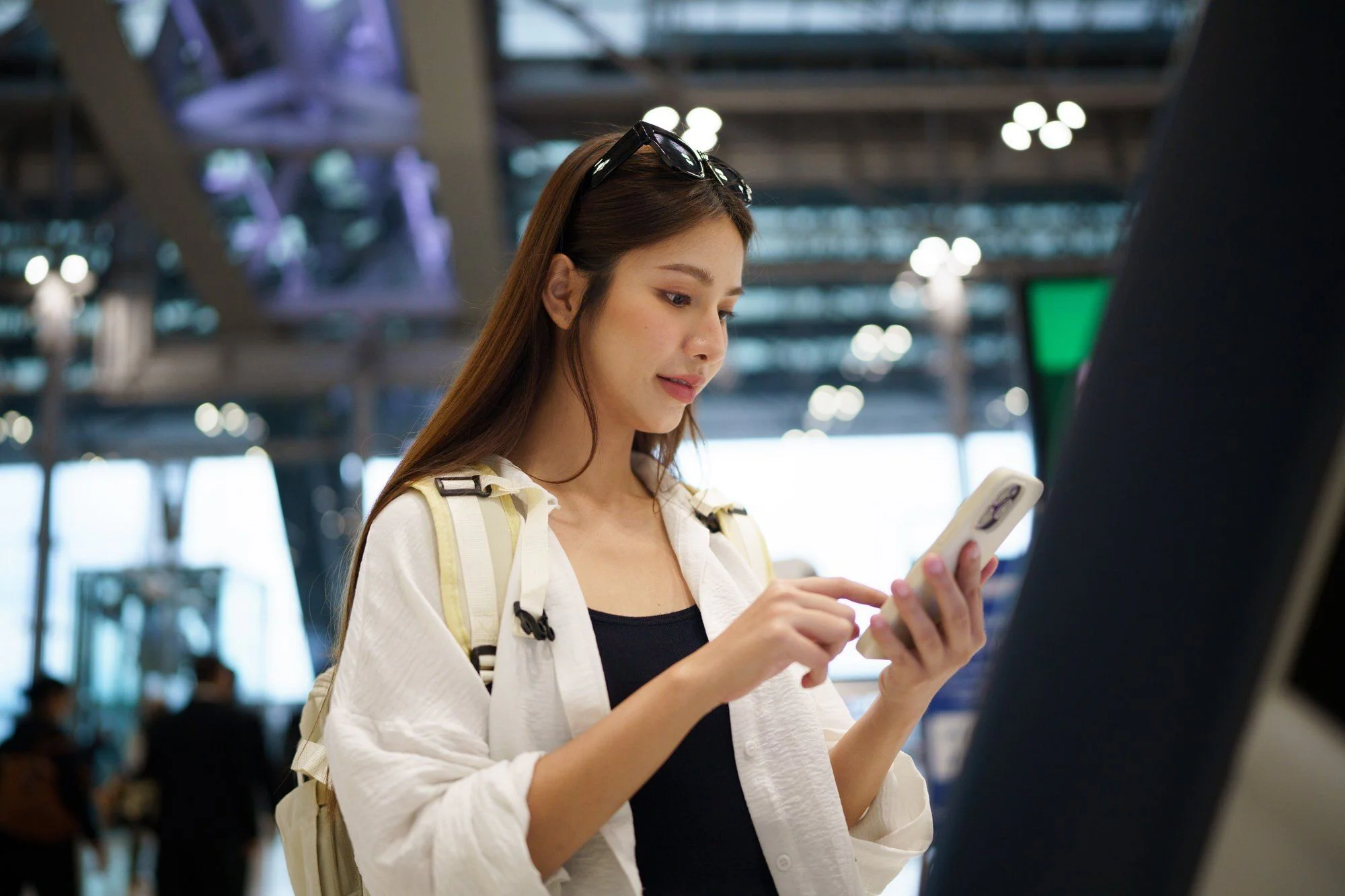 Resenär checkar in online med smartphone och självbetjäningskiosk på internationell flygplats