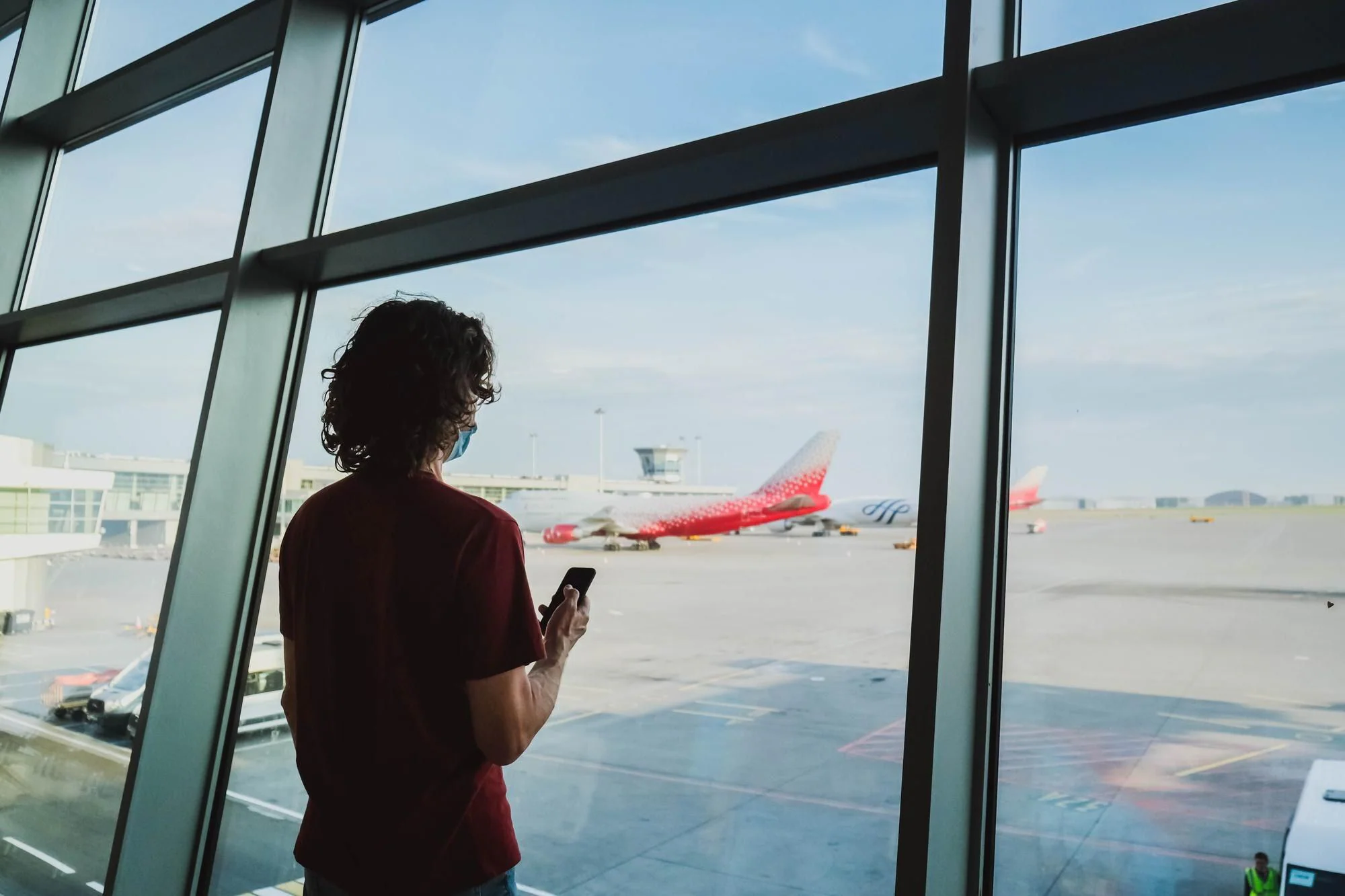 Resenär på flygplats med flygplan i bakgrunden inför val mellan direktflyg och anslutningsflyg