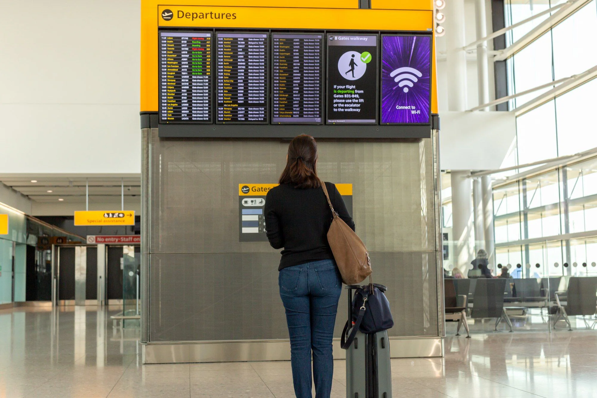 Resenär med bagage tittar på flygtidtabellen under en mellanlandning på internationell flygplats