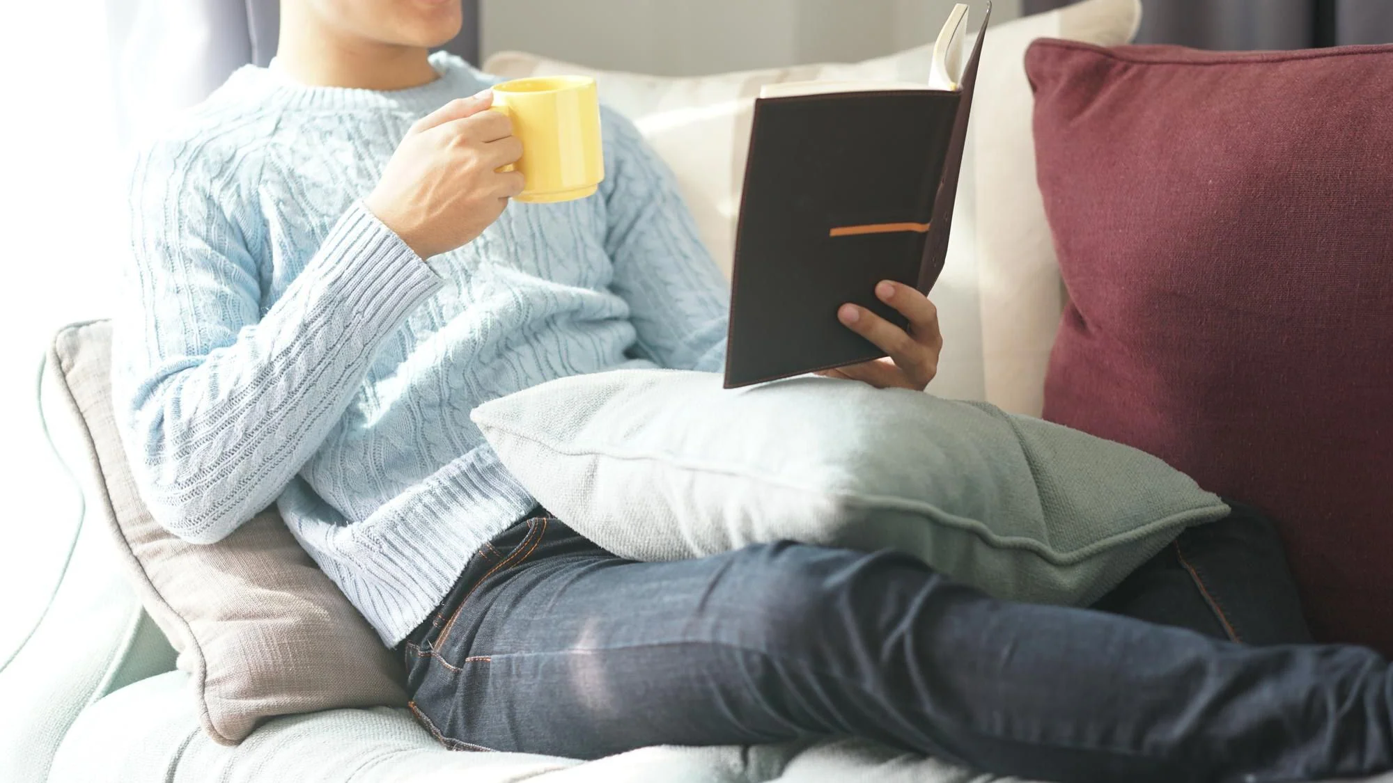 Person läser en bok och vilar i soffan hemma